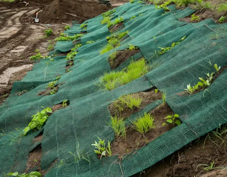 Erosion control mat supporting soil retention and vegetation growth on a stabilized slope